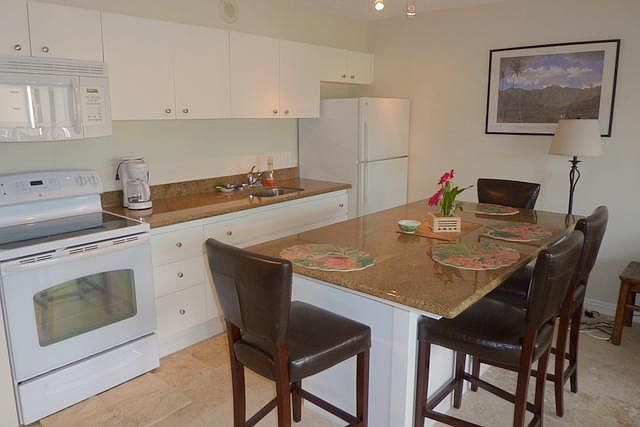 Complete kitchen with dining counter, microwave, stove and refrigerator.