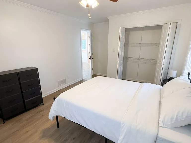 Spacious bedroom with ceiling fan, wood-look flooring, and a wide open closet with shelving for easy organization.