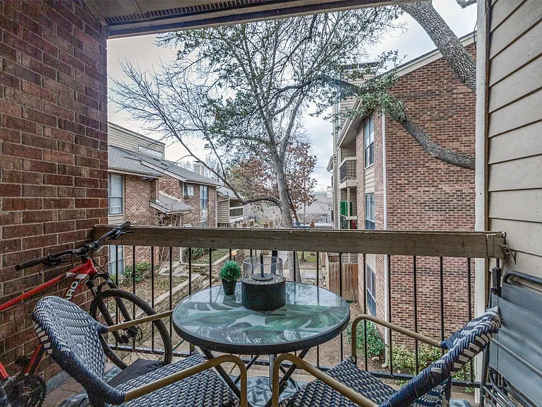 Private balcony featuring a wood railing with black metal balusters, brick exterior wall, and wood-finish siding