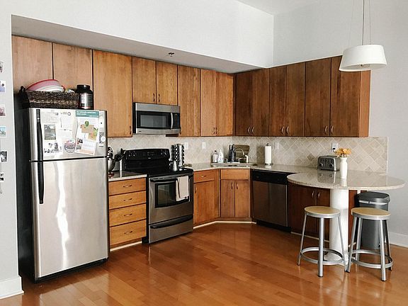 Kitchen with electric stovetop, built-in microwave, dishwasher, stainless steel sink with garbage disposal, updated refrigerator with water and ice dispenser (not pictured), granite countertops with tiled backsplash. All appliances stainless steel.