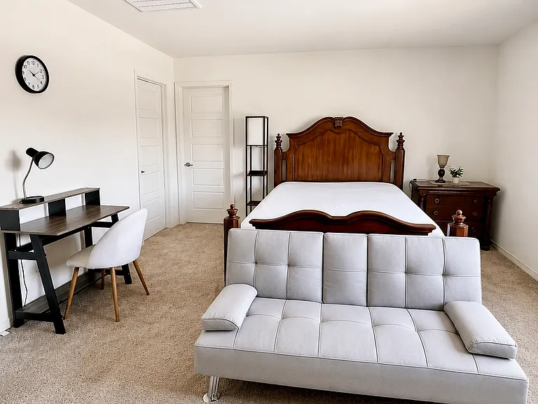 Master bedroom with queen bed, foldable sofa bed, and workspace