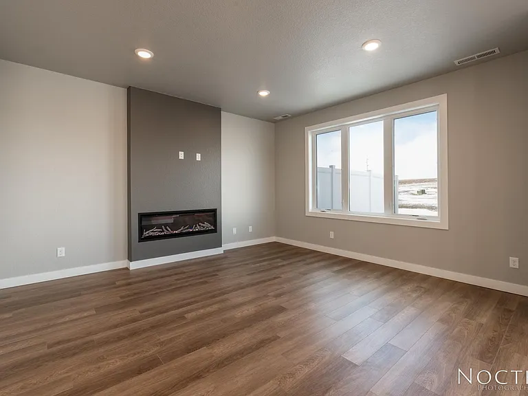 Living room with electric fireplace off the open kitchen and dining space. (Photo of another unit with similar finishes and quality.)