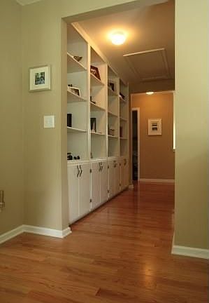 Upstairs hallway with built in storage and shelving, wood flooring in hall