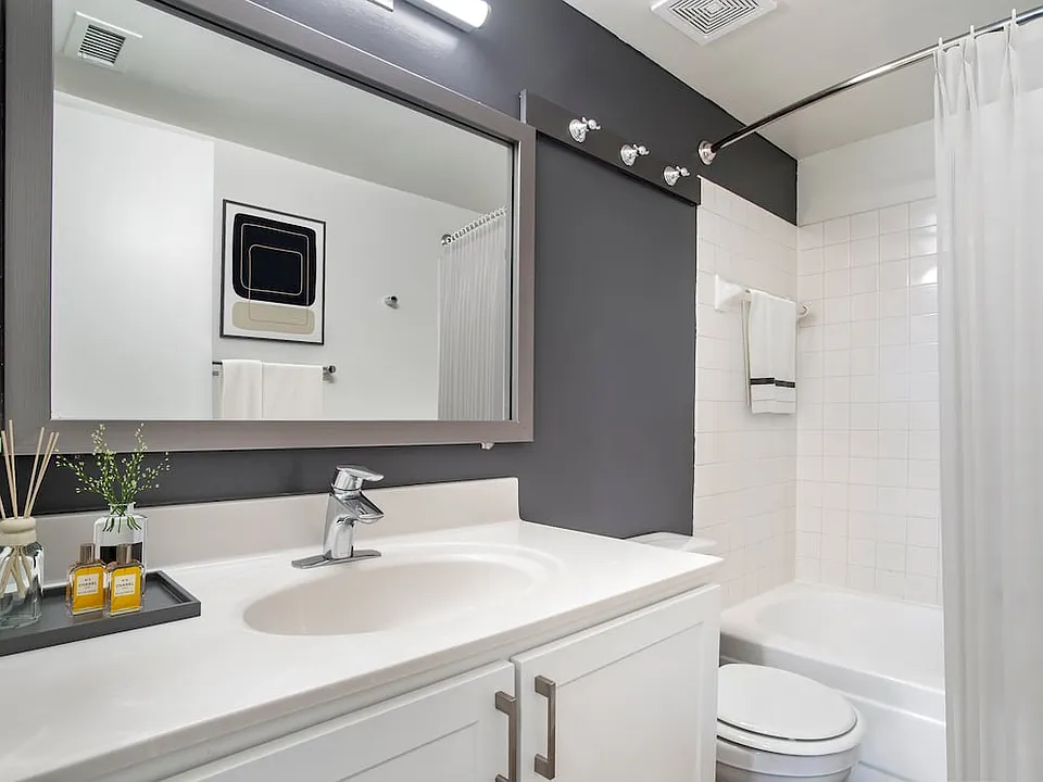 Renovated Package II bath with white countertops and cabinetry, accent wall, and hard surface flooring