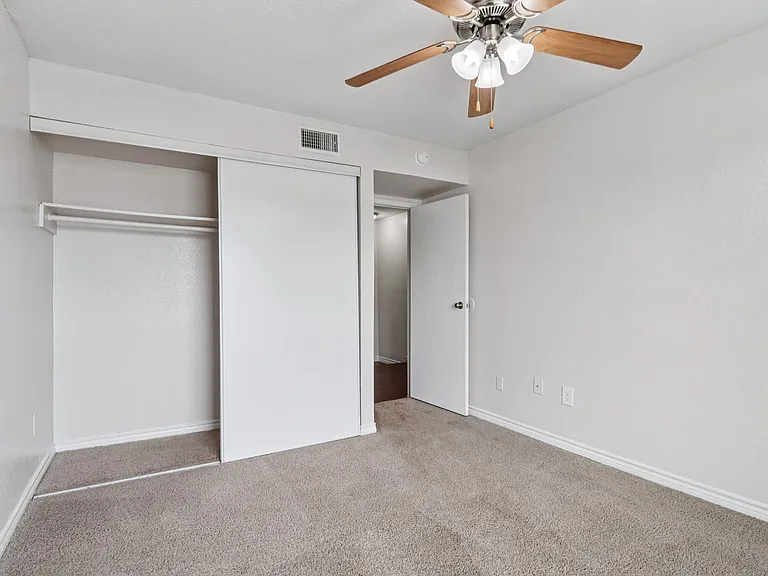 Bright and airy bedroom with soft carpet flooring, a ceiling fan, and a spacious closet. Bright and airy bedroom with soft carpet flooring, a ceiling fan, and a spacious closet.