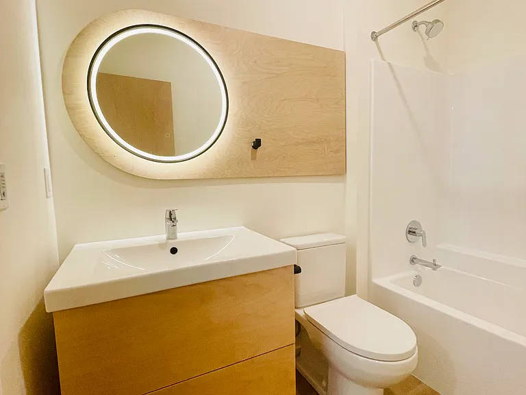 Mirror with integrated and color adjustable LED lighting hangs above vanity cabinet with drawers.