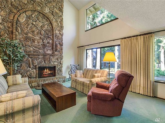 The formal living room features a vaulted ceiling, fireplace with floor to ceiling rock surround, and a slider that leads the backyard and patio.