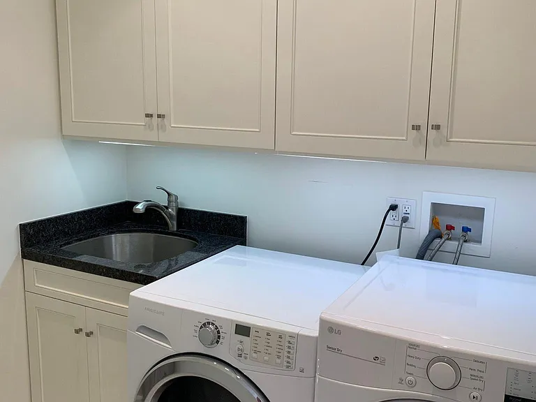 In-unit laundry room with cabinets and utility sink