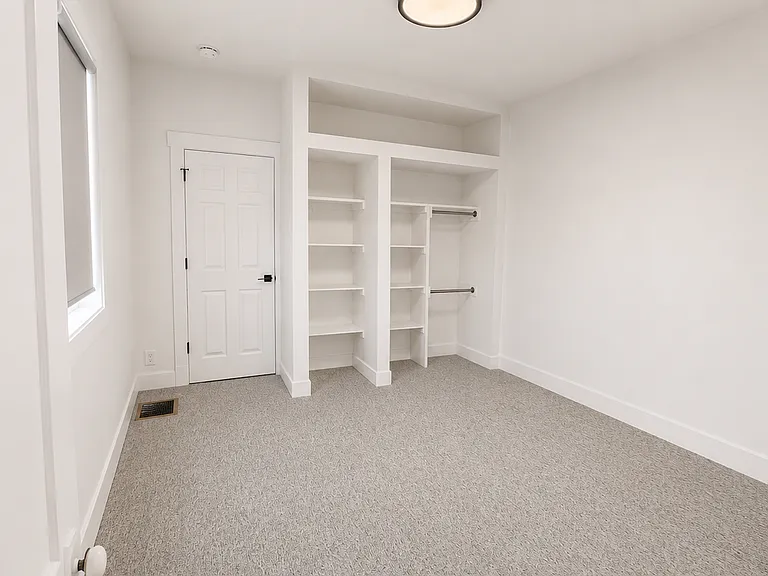 Spacious second bedroom featuring plush carpet and convenient built-in shelving/storage.
