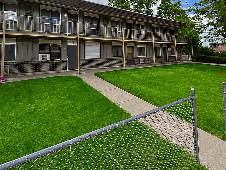 Charming two-story apartment complex with well-maintained green lawns and a welcoming pathway, perfect for comfortable living.