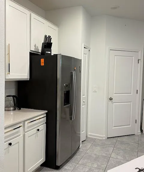 Kitchen features white cabinetry, ample counter space, and a side-by-side refrigerator with in-door ice and water.