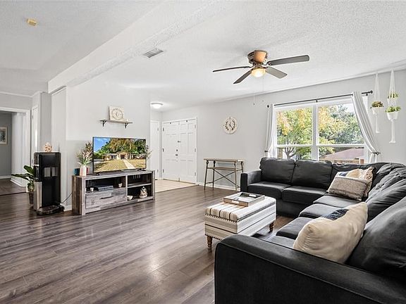 Living room with ceiling fan, a textured ceiling, and dark hardwood / wood-style floors