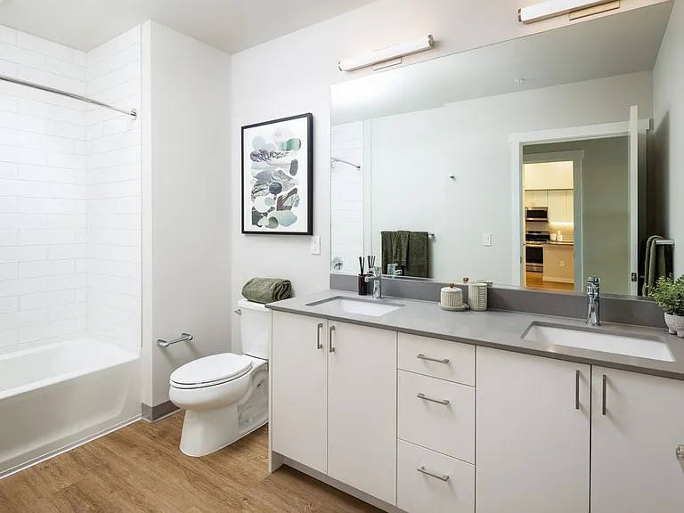 Bath with grey quartz countertops, white cabinetry, and hard surface flooring