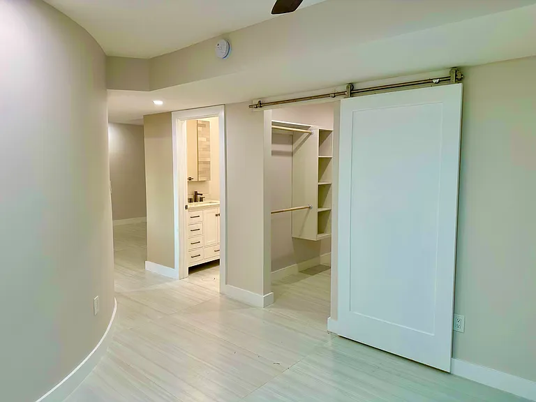 Walk in closet and bathroom as seen from bedroom with view towards living room