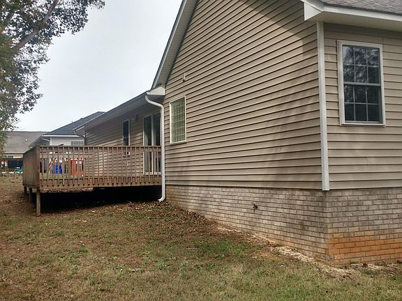 Another rear view of home, deck, and trees