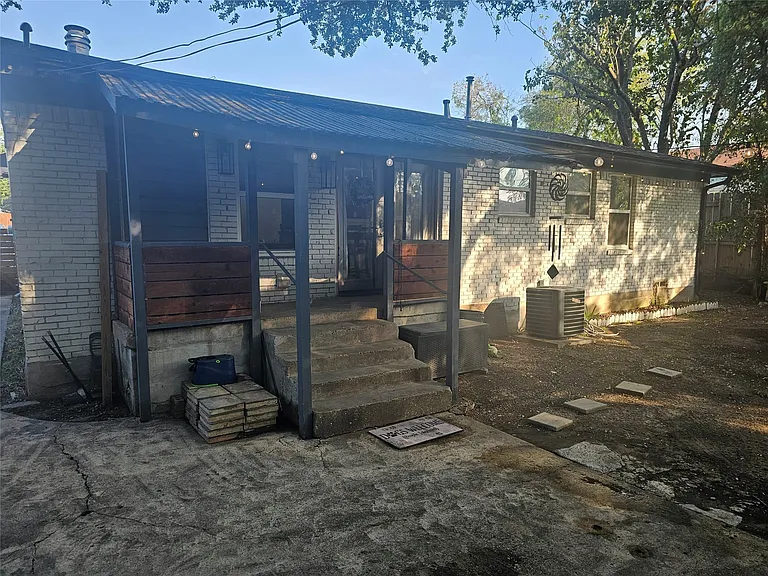 Back of house with brick siding and a metal roof