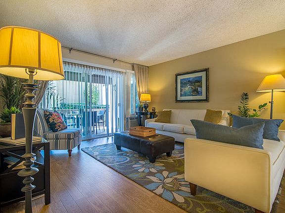 Staged living room with hardwood-style vinyl flooring and sliding glass door leading to balcony.