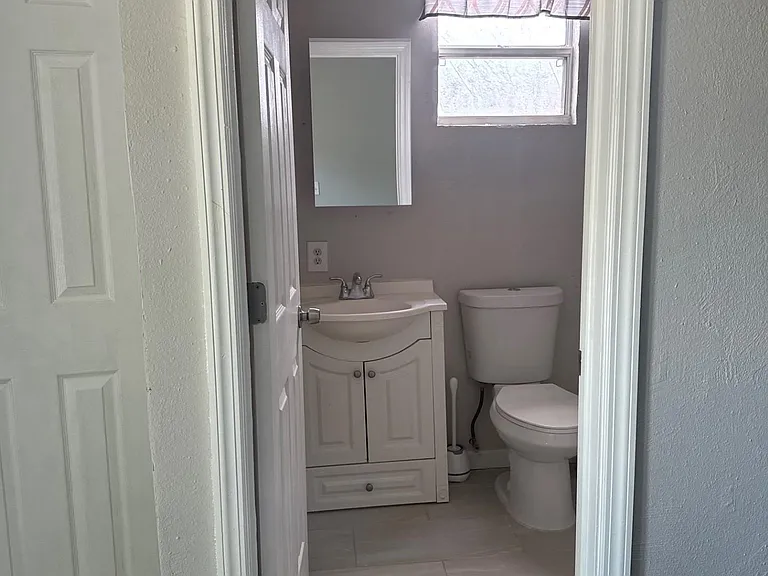 Efficient bathroom with a single-sink vanity, framed mirror, and window for natural light plus durable tile flooring.