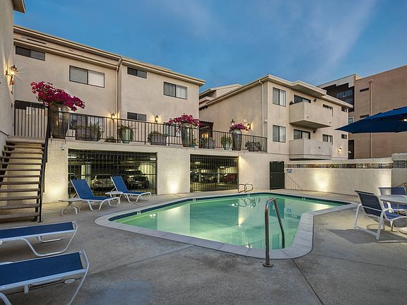 Apartments in Encino, CA - Pool with Lounge Chairs and Building Exteriors Lit Up at Night