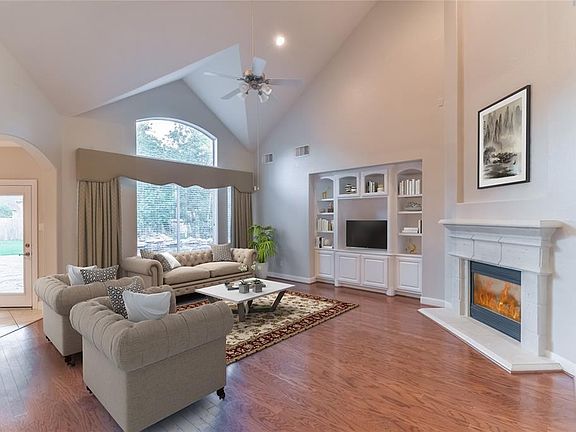 Cozy Family room/Den with vaulted ceiling, built-in shelves, cast stone Fireplace, gleaming hardwood floors, and windows over looking the beautifully landscaped backyard with pool/spa.