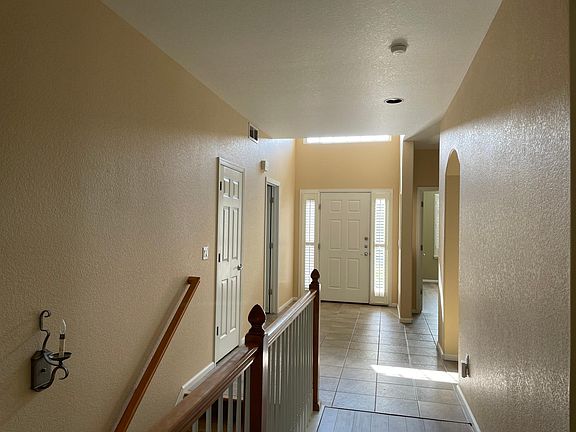 Entrance of the front door, laundry room at the right that connects to the garage. Guest room at the left with a full bathroom next to it. Stair down to the basement.