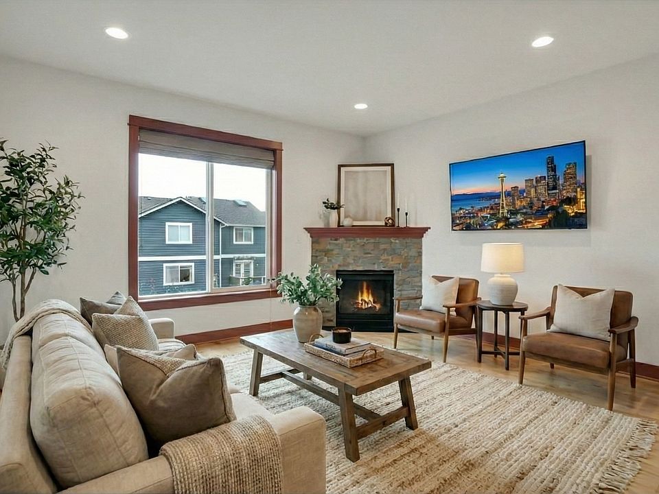 Light-filled living room with hardwood floors and a cozy gas fireplace. Open, inviting layout perfect for relaxing or entertaining, with large windows and a warm, welcoming atmosphere you'll love coming home to.
