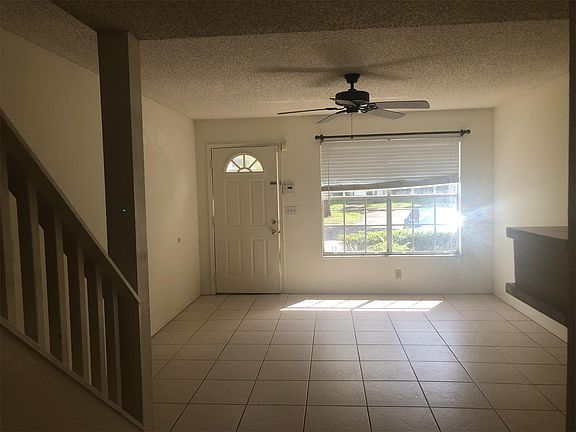 Large, tiled living room with ceiling fan and fireplace