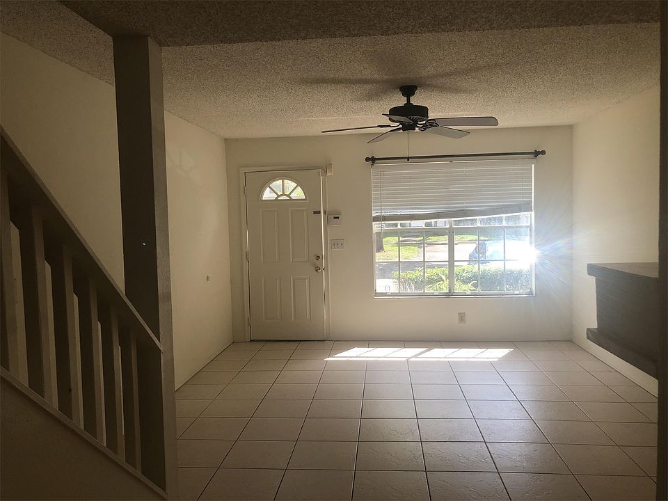 Large, tiled living room with ceiling fan and fireplace