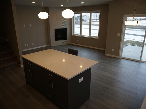 Stunning kitchen opening into the large living space with fireplace and a sliding door to the patio with a beautifully landscaped yard.