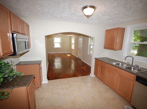 Renovated kitchen features new cabinets, tile floor and Silestone counters