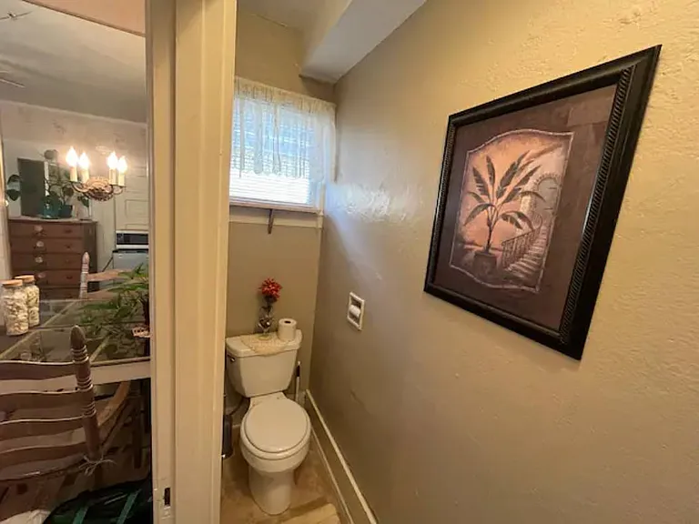 Private toilet within en suite bathroom looking from doorway towards vanity and jetted tub at left.