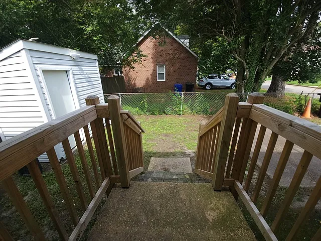 Fenced backyard with driveway and storage shed.