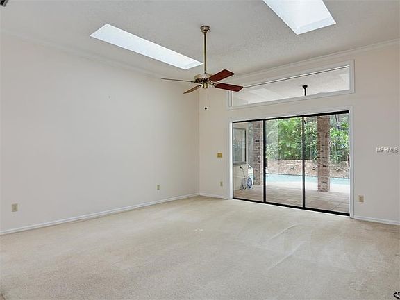 Formal living room with skylights and sliding glass door leading out to the covered screen enclosed pool and spa