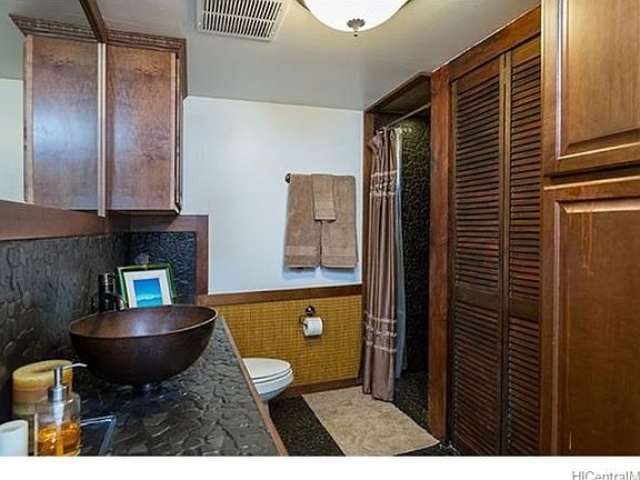 Upgraded bathroom featuring river rock floor, shower and counters, vessel sink and bamboo wainscotting.