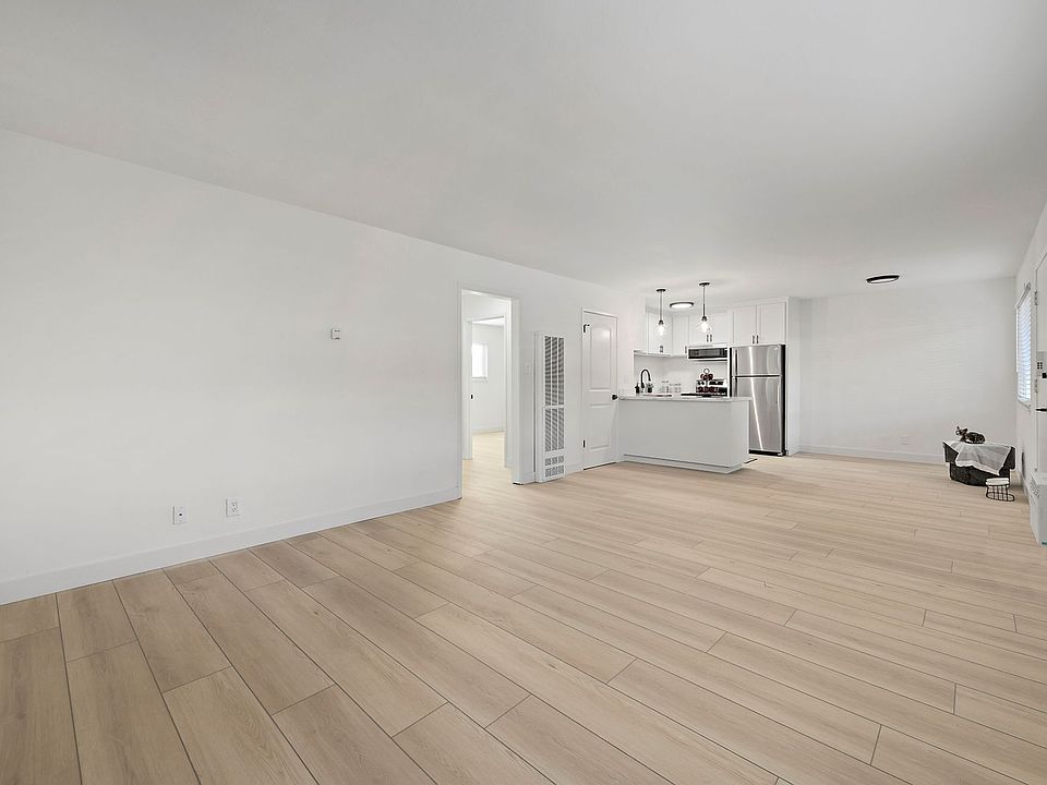 This spacious, light-filled living area offers an open-concept layout with wide-plank wood-style flooring throughout