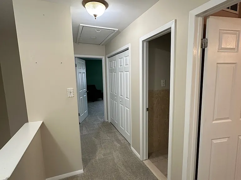 View from end of second floor hallway, looking toward master bedroom. Doorway to the right is second bedroom, next doorway is hall bathroom, double doors are Washer/Dryer, opposite is large linen closet, and master bedroom at the end.