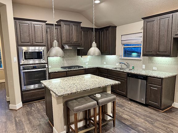 Modern kitchen with granite countertops, large island, stainless steel appliances, and plenty of cabinet space _ perfect for cooking and entertaining.