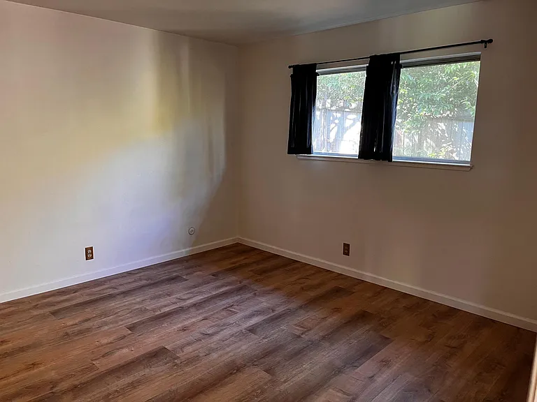 The bedroom has a large window with a view of the backyard.