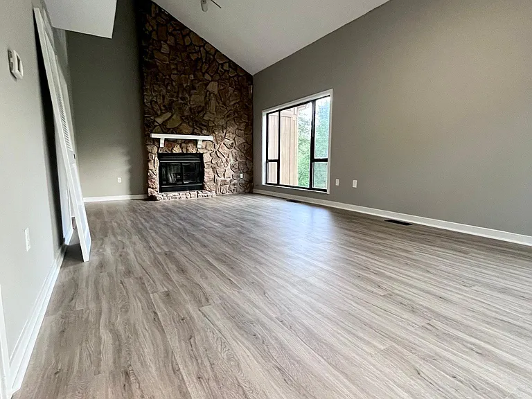 Main level Great Room space featuring high ceilings, original (working) fireplace, new flooring, fresh paint and tons of natural light!
