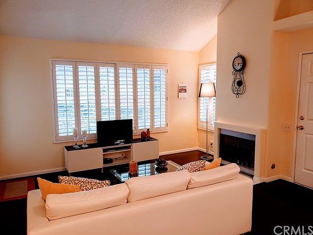 Spacious living room with gas fireplace, gorgeous dark work flooring with shutters and access to balcony.