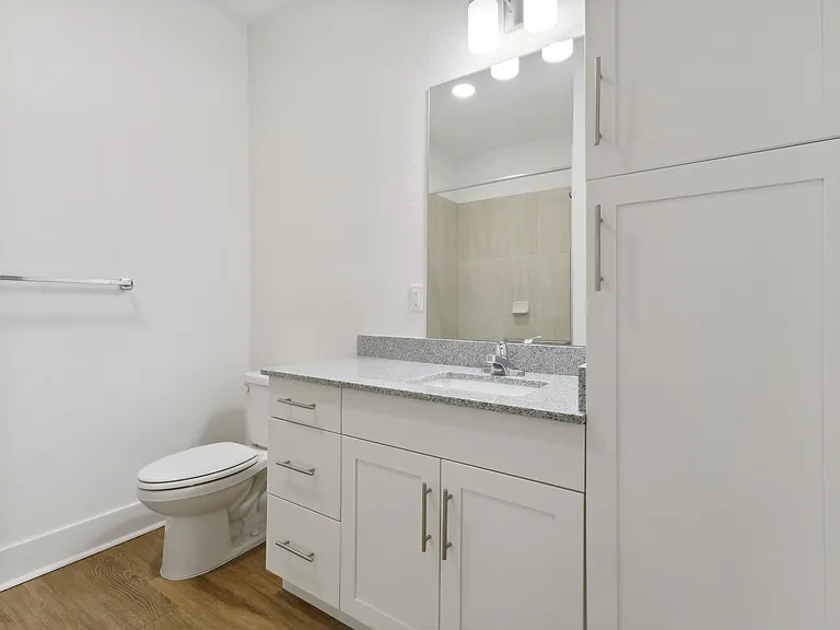 Modern bathroom featuring sleek white cabinetry, elegant granite countertop, and polished chrome fixtures, creating a bright, inviting space.