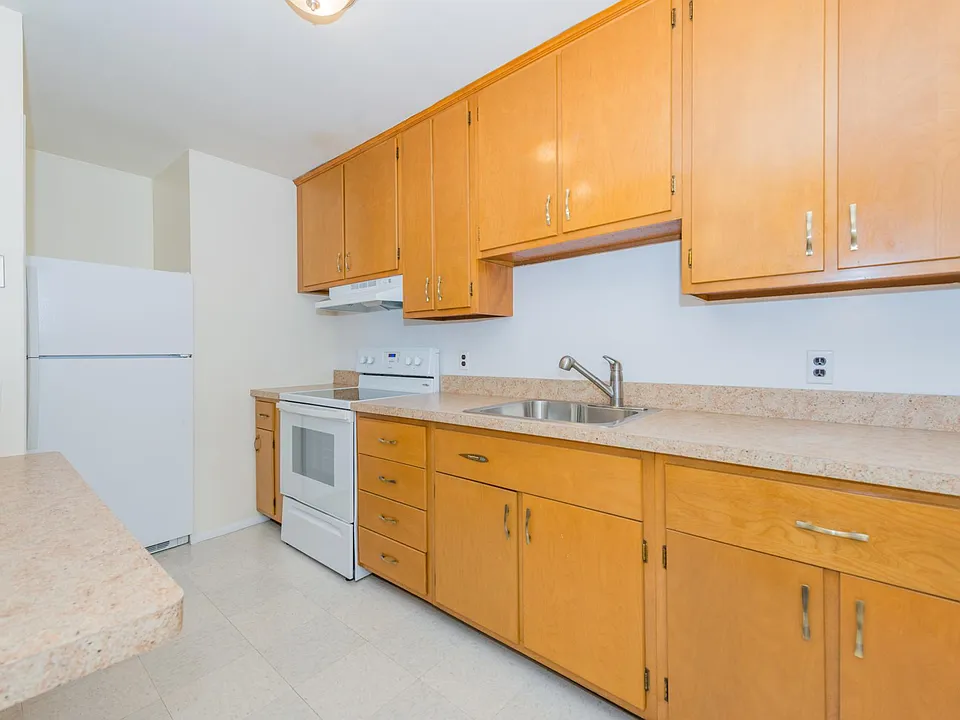 Galley Kitchen with refrigerator, electric stove and pantry.