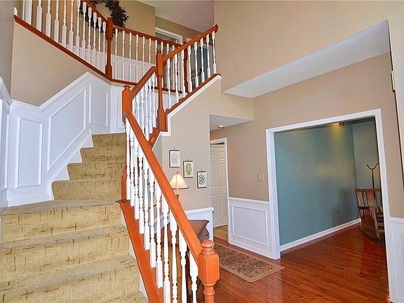 Two-story entry with hardwood floor, guest closet and wainscoting.