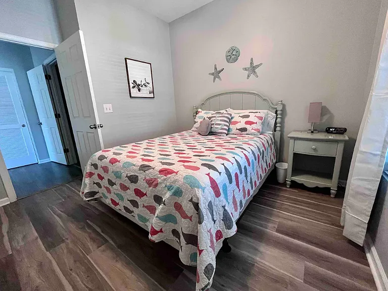 The second bedroom features a queen bed, dresser, closet, smart TV and ceiling fan.