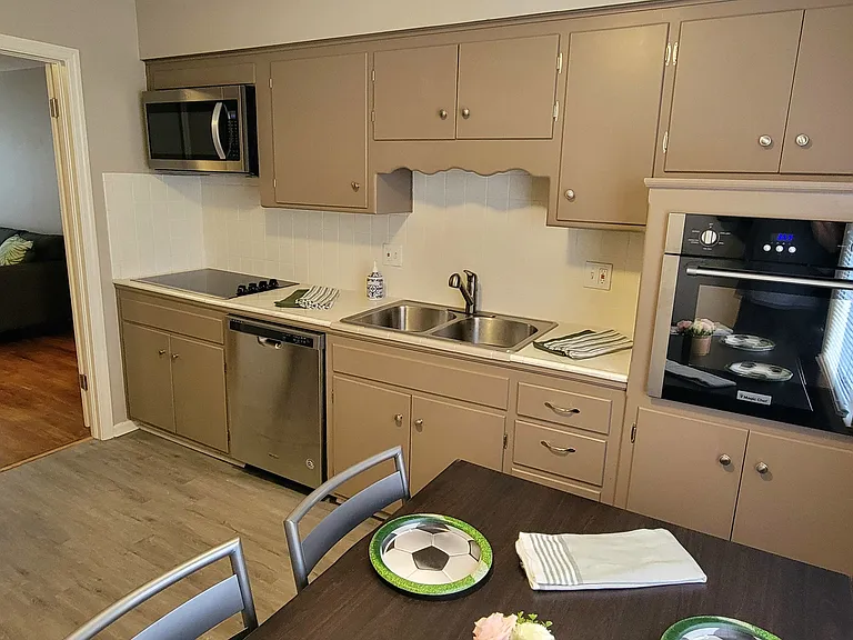Kitchen Area leading into livingroom Area with Stove, Refrigerator, Microwave, Dishwasher, stainless steel Sink, dining table, chairs, new towels, and plenty of cabinet space.