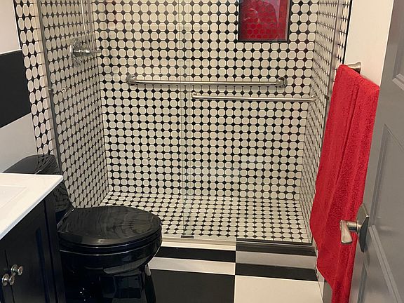 Totally remodeled bathroom. Safety bars in tile shower. Tile floor. Pop of color niche!