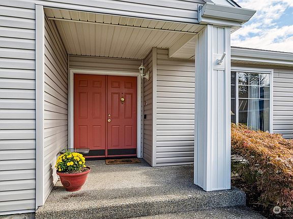 A large covered front porch shelters guests and deliveries from the elements.>