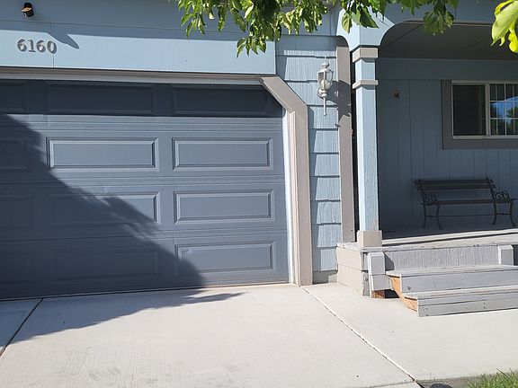 View of private Ranch style home, with nice front porch, two car garage, with newer driveway, front area has sprinklers and mature tree, bushes and ground covering