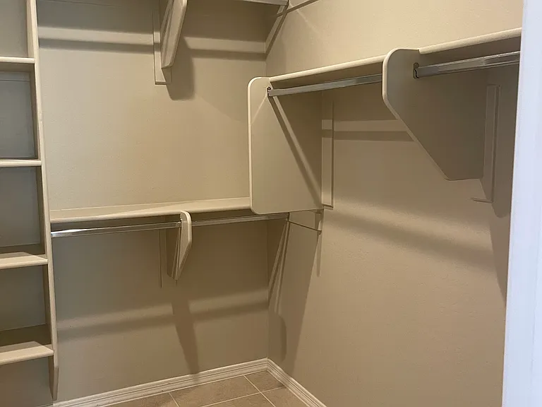 Partial picture of master closet with multiple built in organization and wardrobe rods.