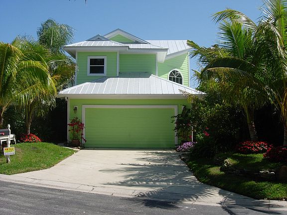 front of house, nicely landscaped with coconut trees